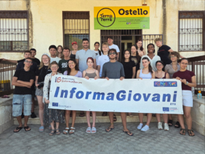 Gruppo di persone in piedi con in mano un banner di informa giovani